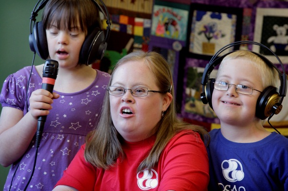 Three children with head phones and a microphone performing