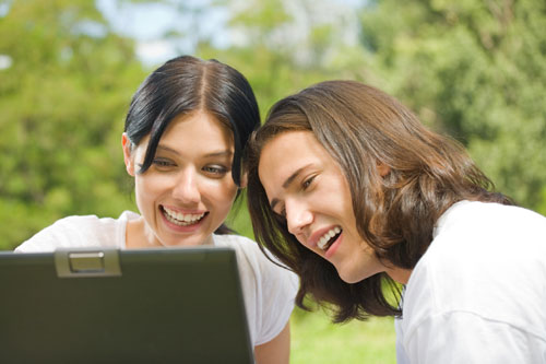 Two people reading a laptop