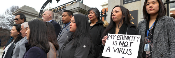 A group of people holding a sign that says - My ethnicity is not a virus