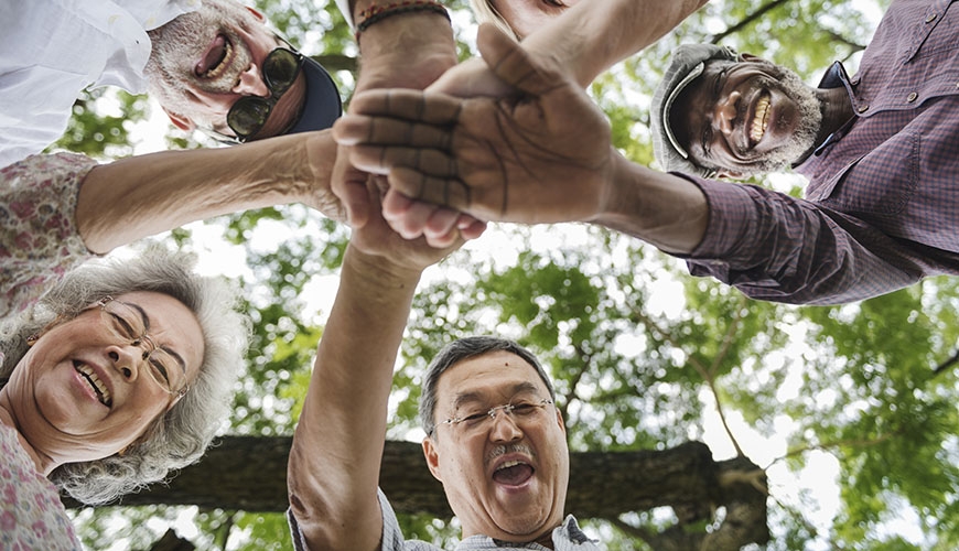 Older people holding hands in an "all for one, one for all" motion