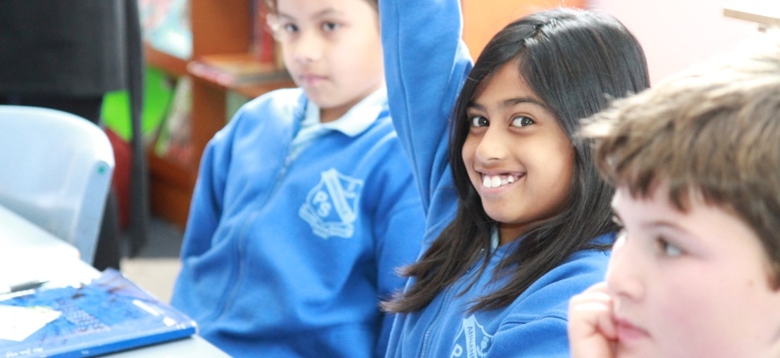 children in class, smiling girl raising her hand