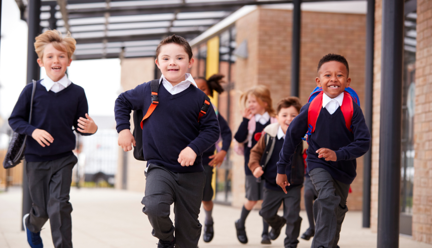 A group of children running at a school, wearing school uniforms