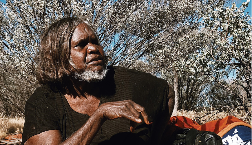 First Nations woman wearing black t-shirt sitting in the bush