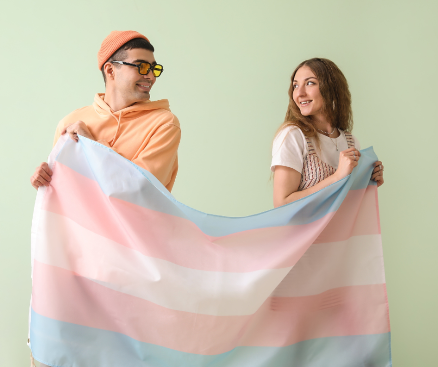 2 young poepl standing behind a trans flag