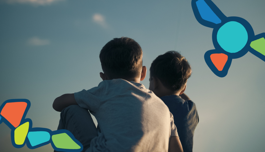 two boys sitting on the groud looking up to the sky