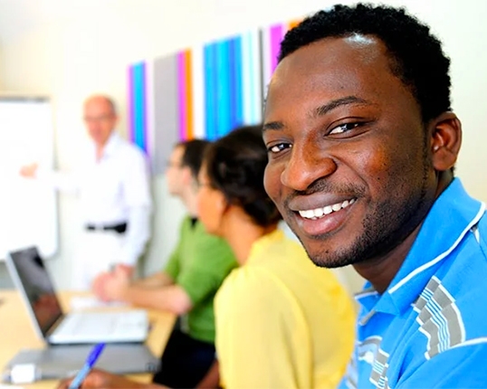 Male in classroom, smiling at camera