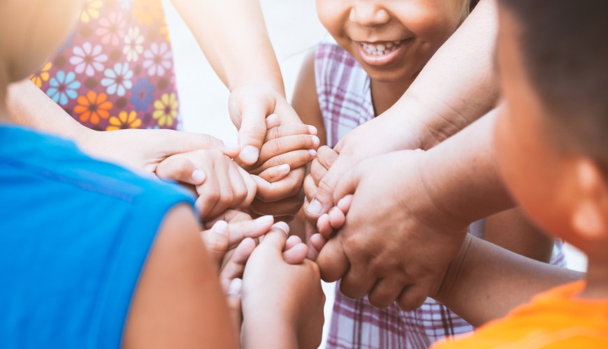 Children and adult holding hands and playing together with unity and teamwork.