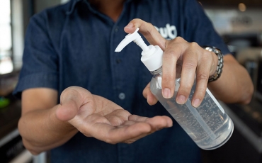 A person holds a bottle of hand sanitiser and pumps it into their hand.