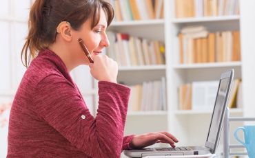 A person with a hearing aid sits working at a laptop