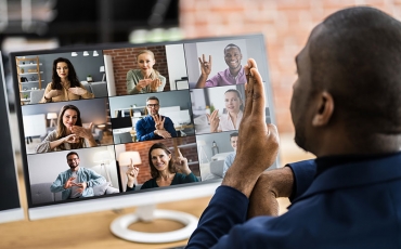 A person in an online meeting uses sign language to communicate with the other participants