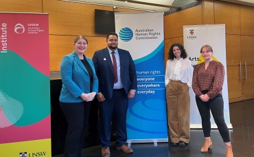 Four people stand besides a banner for the Australian Human Rights Commission.