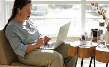 A person sits on the couch at their laptop