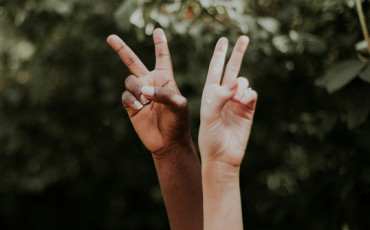 Two hands reaching up making the peace symbol