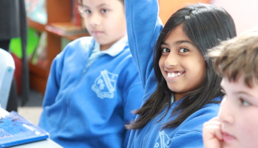 children in class, smiling girl raising her hand