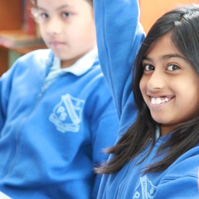 children in class, smiling girl raising her hand