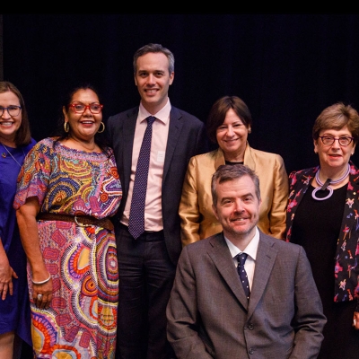 A group photo of all eight Commissioners smiling at the camera. T