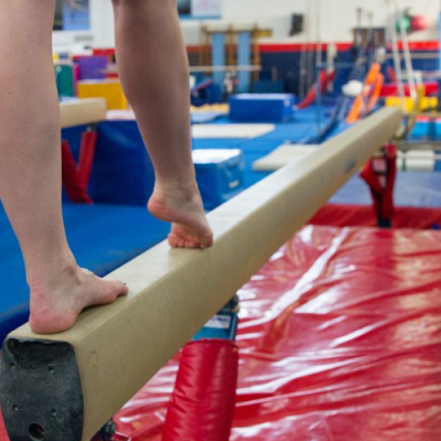 The legs of a child gymnast seen standing on a balance beam.