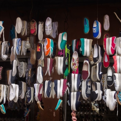 Image of a range of different colours and styles of sneakers hanging in a store front 