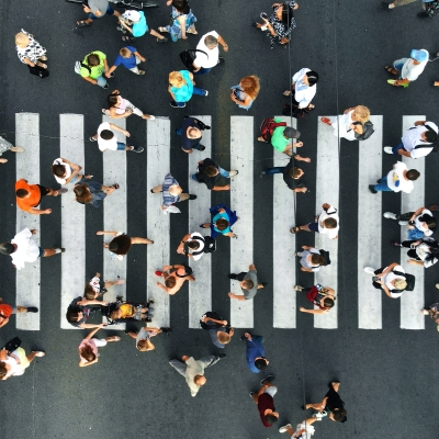 A busy street crossing with dozens of people walking back and forth, as seen from above.