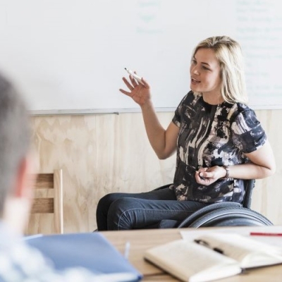 Image of woman in wheelchair in front of whiteboard speaking 