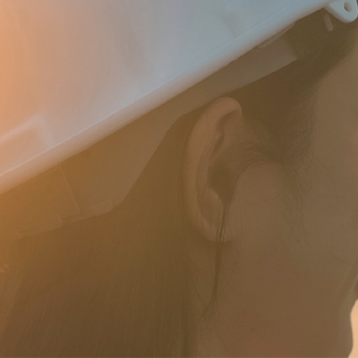 A woman wearing a white hard hat smiles into the distance