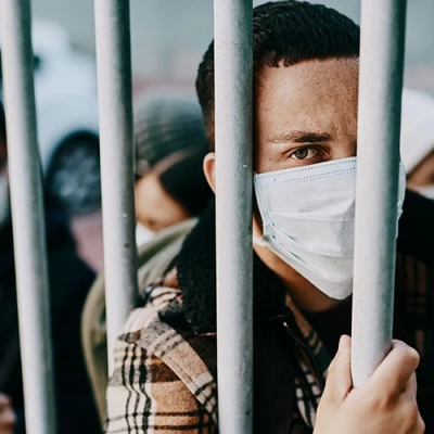 Detainees look from behind steel fence