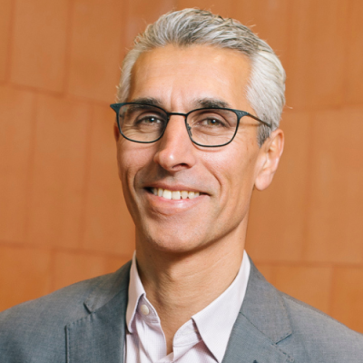 Human Rights Commission President, Hugh de Kretser. Smiling, middle aged man in grey suit with white hair and glasses